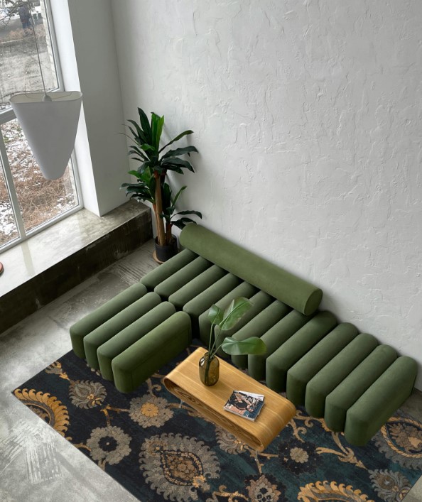 Zielona modułowa sofa zestawiona z ciemnym, wzorzystym dywanem z oferty Dywany Witek.